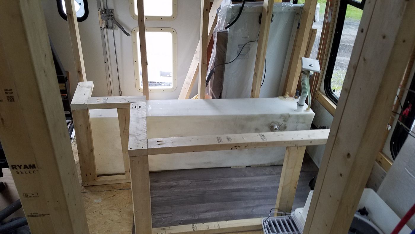 The fresh water tank framed into the build, with the fill hose and fittings connected.