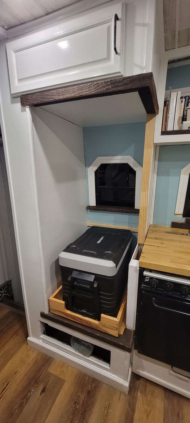 The 12V portable fridge pulled out on its drawer slide next to the propane stove in the finished galley.