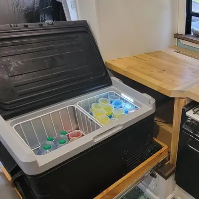 Our 12V fridge open in its pull-out drawer, stocked with drinks