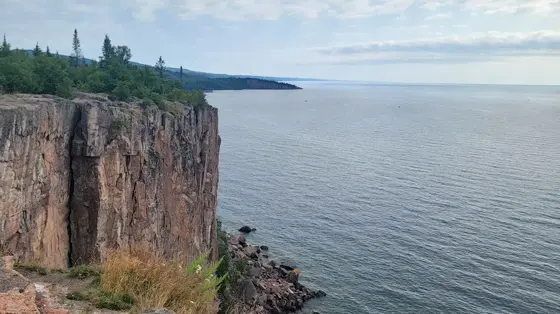 The columnar cliff of Palisade Head above Lake Superior and the rocky shoreline seen from the overlook
