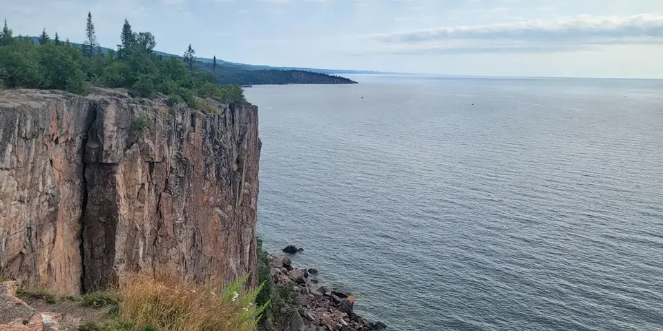 The columnar cliff of Palisade Head above Lake Superior and the rocky shoreline seen from the overlook