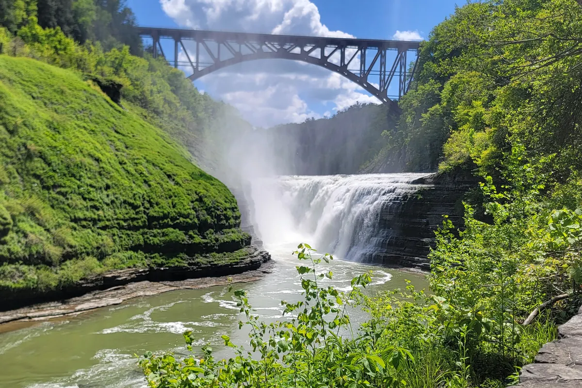 A waterfall in the Genesee River gorge at Letchworth State Park with a railroad bridge above