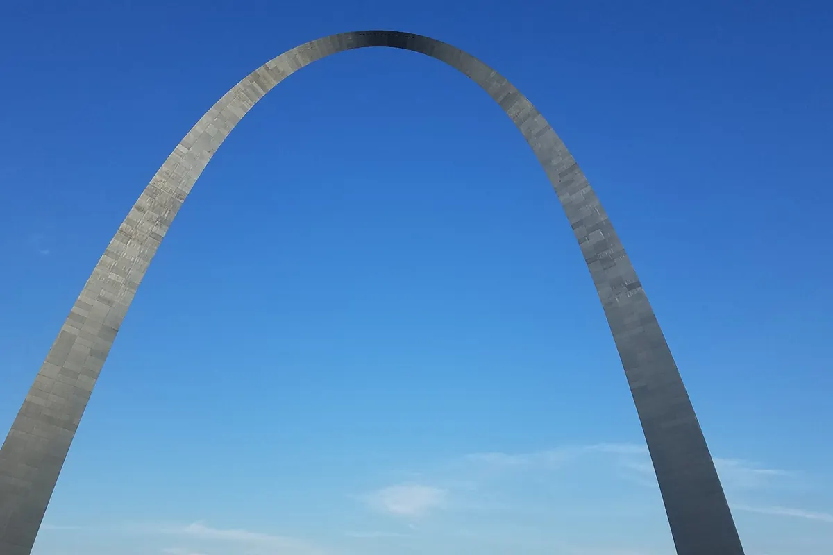 The stainless steel Gateway Arch against a clear blue sky
