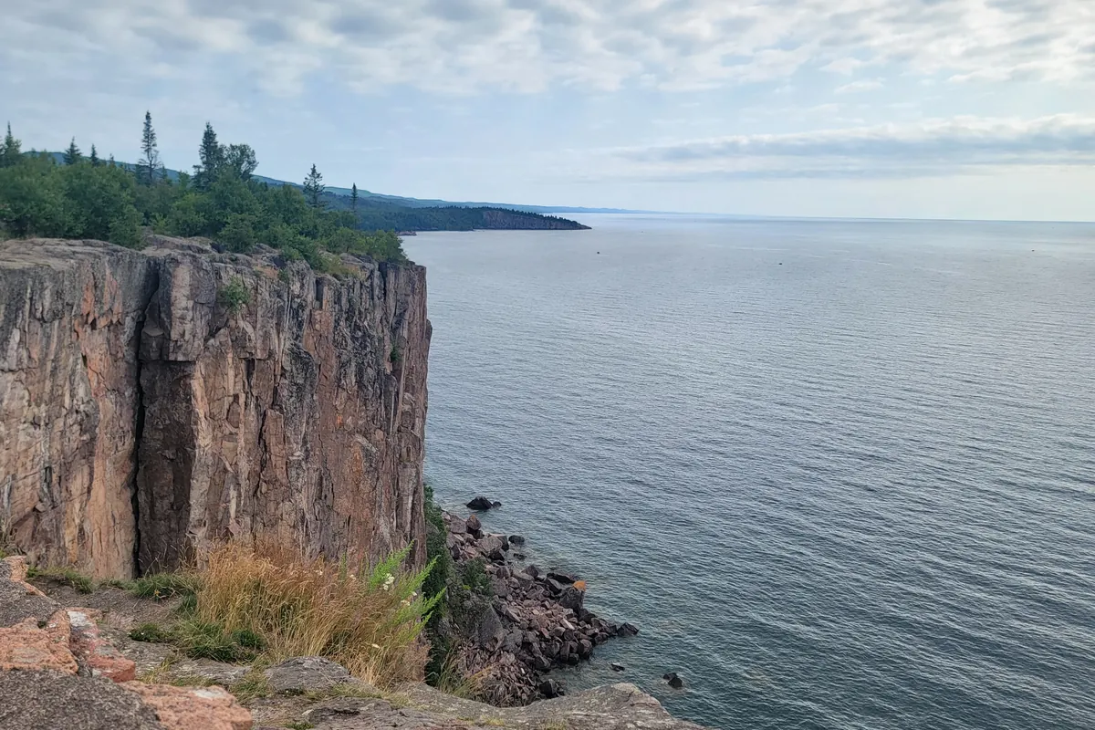 The columnar cliff of Palisade Head above Lake Superior and the rocky shoreline seen from the overlook