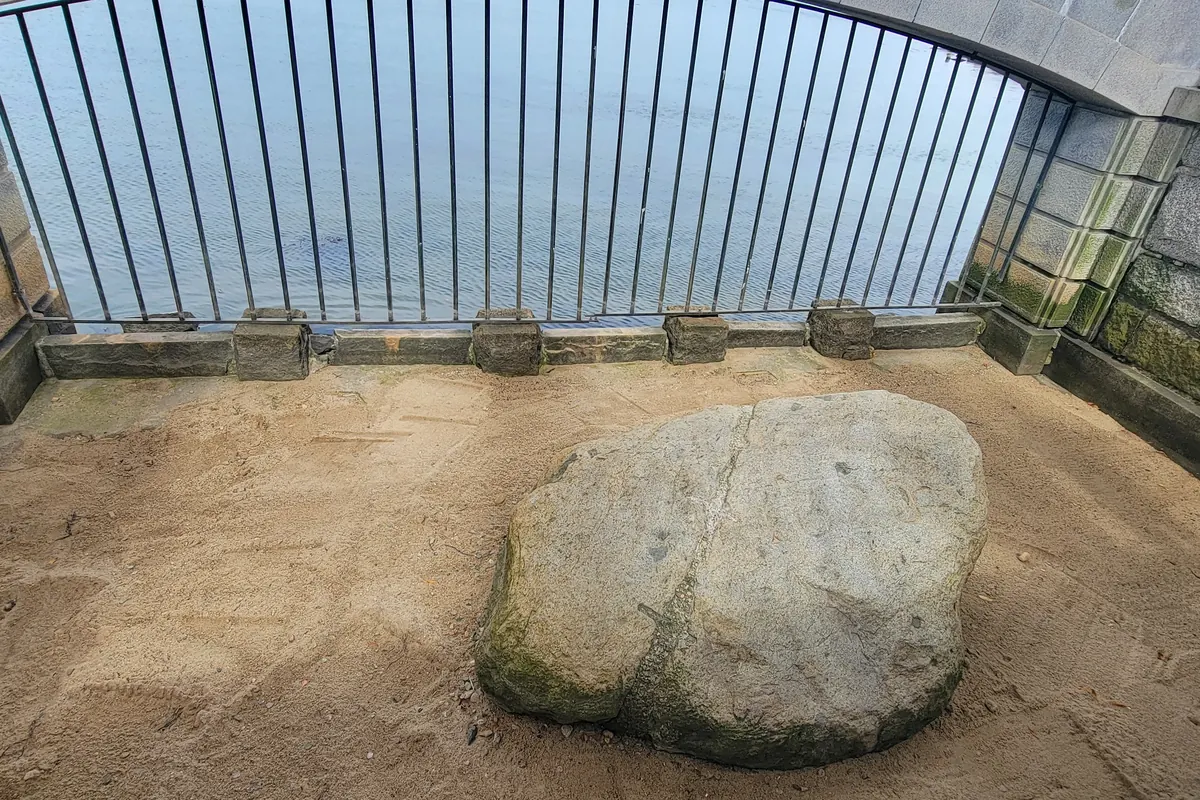Plymouth Rock beneath its granite canopy and the Mayflower II moored in Plymouth Harbor
