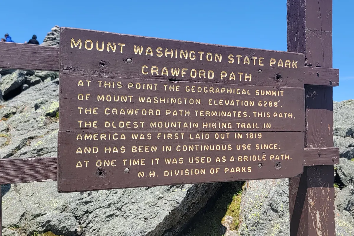 The Mount Washington State Park summit sign and the cog railway train at the summit