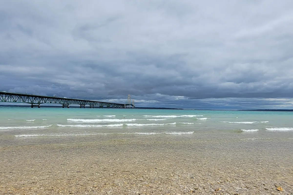 The Mackinac Bridge stretching across the Straits seen from a pebble beach
