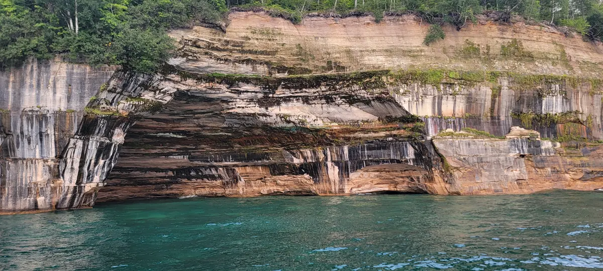 Streaked sandstone cliffs and a sea cave at Pictured Rocks seen from the water